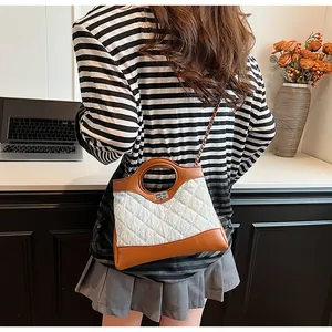 Détail du tissu matelassé et de la poignée ronde du sac en cuir marron avec patchwork