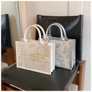 Detail of embroidered butterfly tote bags with textured fabric and top handles