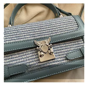 Detail of silver clasp with embossed mythical creature on blue woven handbag