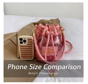 Detailansicht der rosa Pailletten-Beuteltasche neben einem Smartphone zum Größenvergleich