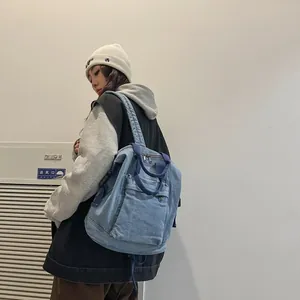 Detail of light blue washed denim backpack showing textile texture and handle straps