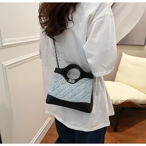 Détail du sac en tweed bleu montrant la texture matelassée, le cuir et le fermoir métallique