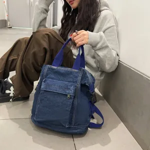 Detailed view of washed denim backpack with blue nylon straps and front zipper pocket