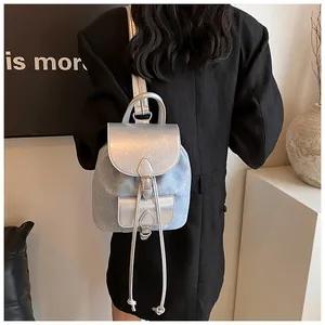Mini PU and denim backpack with silver metallic flap and drawstring on black suit model