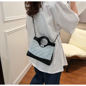 Détail du sac bandoulière en tissu matelassé bleu et cuir noir avec chaîne argentée