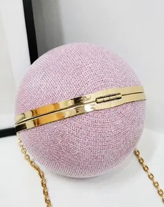 Macro detail of pink sparkling sequins and gold ring handle on a spherical evening clutch bag