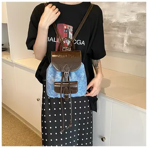 Detail of trendy denim and PU leather patchwork backpack worn by a female model