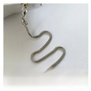 Détail de la bandoulière chaîne serpent argentée avec fermoir sur sac acrylique blanc