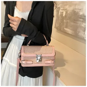 Detail of light pink woven handbag with heart-shaped silver buckle on beige background