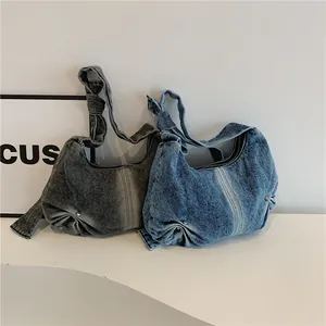 Detail showing two washed denim hobo bags with knot straps in grey and blue colors