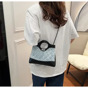 Détail du sac en denim matelassé bleu avec garniture en cuir noir et fermoir rotatif