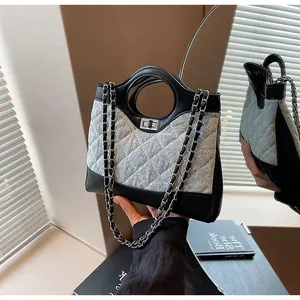 Détails du sac seau en denim bleu avec surpiqûres matelassées et chaîne en métal