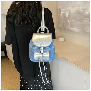 Detail of trendy mini backpack in denim and silver PU leather worn by a model