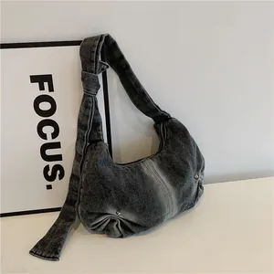 Minimalist denim crescent shoulder bag with knotted strap and stud details
