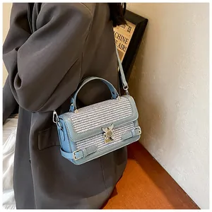 Detail of light blue woven handbag featuring a heart-shaped metal lock and leather handle