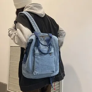 Close-up of a light blue denim backpack with dark blue straps on a person's shoulder