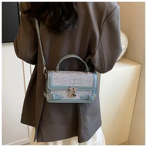 Blue and white woven mini square bag shown as a crossbody on model in minimalist setting