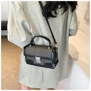 Detail of trendy woven small square bag with silver metal clasp and leather strap
