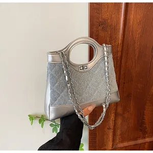 Détail de la poignée argentée et du tissu denim bleu matelassé avec chaîne