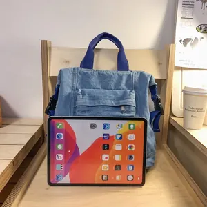 Detailed view of washed denim backpack showing metal zipper pocket and handle