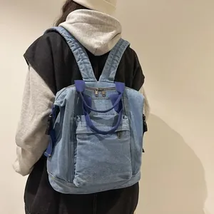 Rear view of a model wearing the blue washed denim backpack with double top handles
