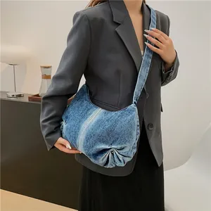 Detail of blue denim crescent bag with pleated bottom and stylish faded stripe texture