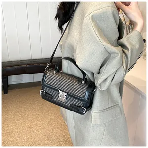 Detail of a chic tweed handbag with silver hardware worn over a grey blazer jacket
