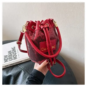 Détail d'un sac seau à paillettes rouges avec fermeture à cordon et garniture dorée