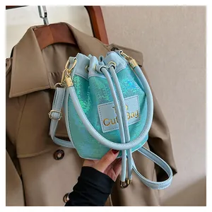 Détail du sac seau à paillettes bleu clair avec cordon et patch en cuir logo