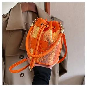 Détail du sac seau à paillettes orange avec cordon de serrage et écusson en cuir