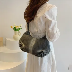 Close-up of grey washed denim shoulder bag with vertical stitching and silver rivet details