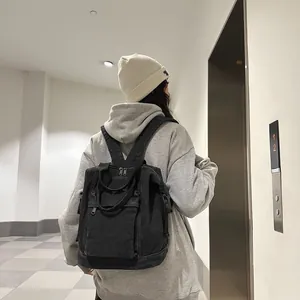 Japanese style washed black canvas backpack shown on a model in a minimalist indoor setting
