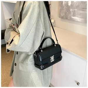 Detail of black crossbody bag with textured fabric flap and silver animal clasp hardware