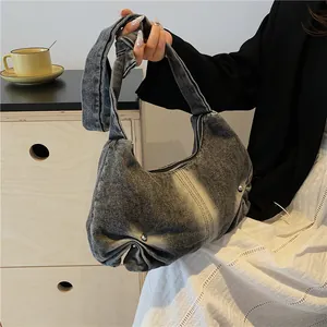 Detail of grey washed denim baguette bag featuring side pleats and pearl embellishments