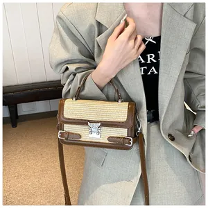 Detail of a beige woven and brown leather crossbody bag featuring a silver metal buckle