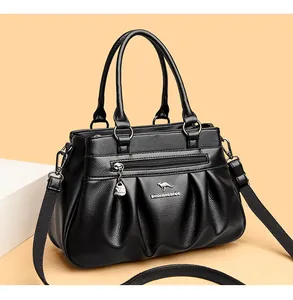 Detail of black pleated faux leather handbag with golden kangaroo logo and heart pendant