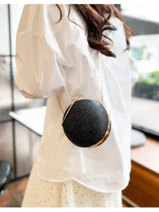 Détail d'un sac de soirée sphérique noir à paillettes avec bandoulière dorée