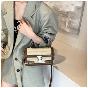 Detail of straw woven crossbody bag with brown leather trim and silver metal buckle