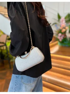 Pochette de soirée argentée scintillante avec chaîne dorée portée par un modèle