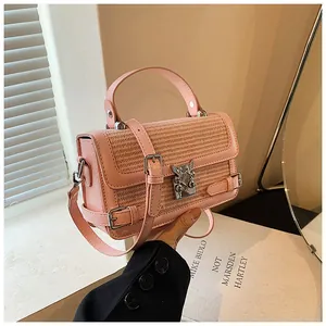 Close-up of pink leather handbag with silver metal buckle and woven texture detail