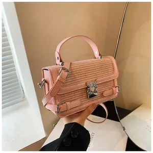 Close-up of pink woven handbag featuring decorative straps and silver angel lock