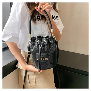 Détail du sac seau à paillettes noires avec lettrage doré sur empiècement cuir