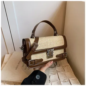 Detail of woven straw and brown leather shoulder bag with metallic lock closure