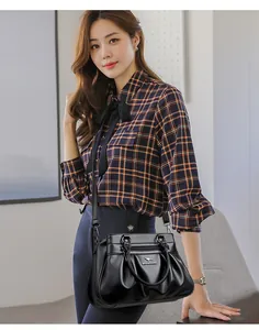 Detailed view of black pleated crossbody bag with pebble texture and metallic kangaroo logo