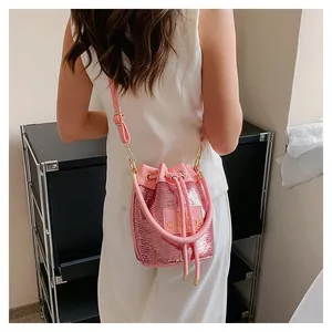 Détail du sac seau à paillettes roses avec cordon de serrage et écusson en cuir brodé