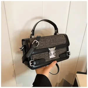 Detail of woven fabric texture and silver heart wing metal buckle on small square bag