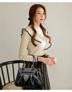 Detailed view of the black lychee grain leather texture and pleated design with metal logo