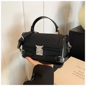 Detail of black woven leather handbag with silver heart buckle and metal accents