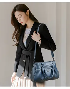Detail of dark blue pleated handbag showing leather texture and metallic kangaroo logo