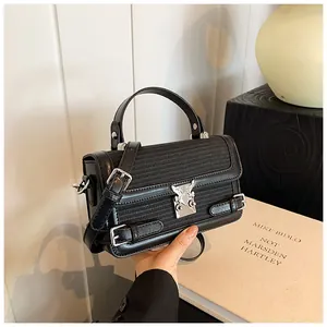 Detail of black woven leather handbag with silver heart-shaped lock and buckle strap